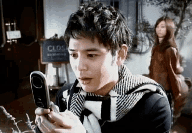 a man looking at a cell phone in front of a sign that says clos