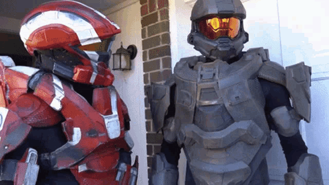 a man in a red helmet stands next to a man in a grey helmet