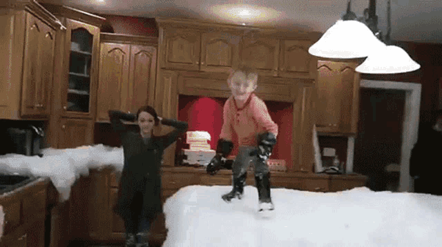 a boy and a girl are jumping in the air in a kitchen