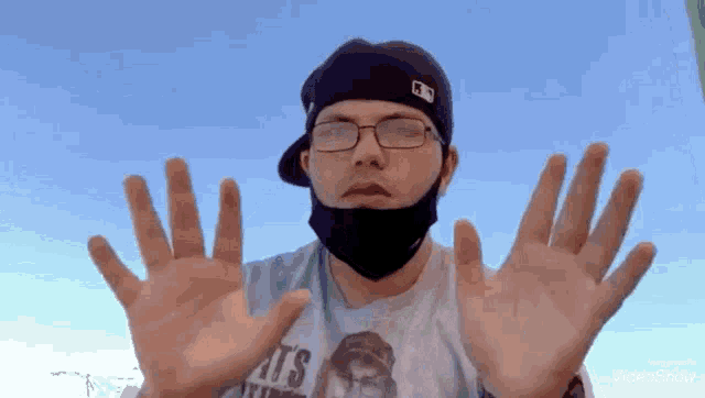 a man wearing a mask and glasses holds his hands up