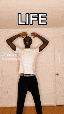 a man in a white shirt stands in front of a wall with the word life on it