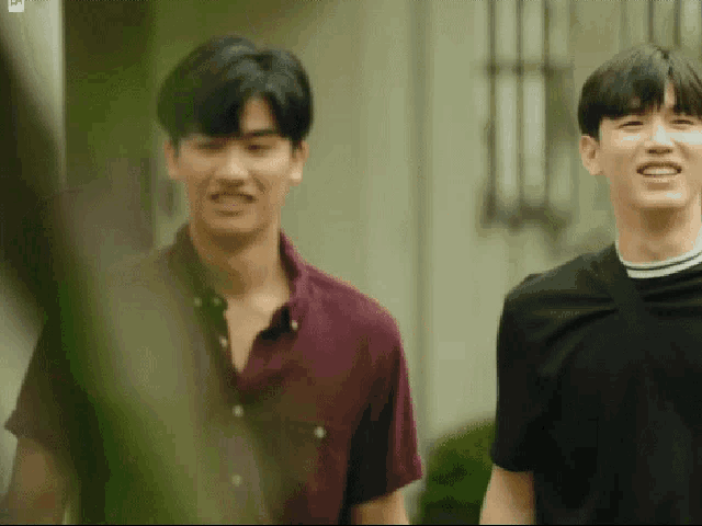 two young men are standing next to each other in front of a house .