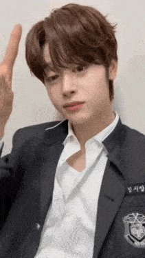 a young man in a school uniform is giving the middle finger