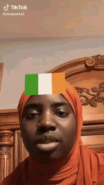 a woman wearing a hijab has a green white and orange flag on her head ..