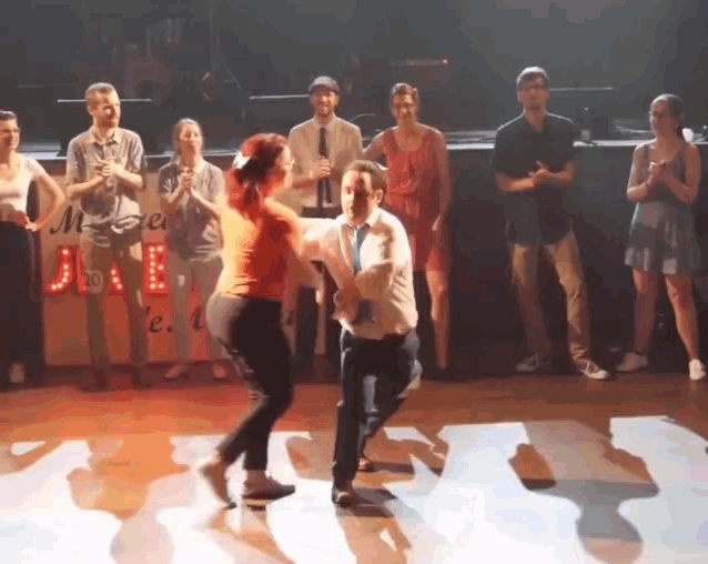 a man and a woman are dancing on a stage in front of a sign that says mega jae