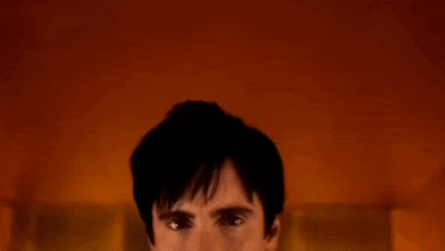 a close up of a man 's face in a dark room with a red background .
