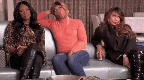 three women are sitting on a couch looking at a tv .