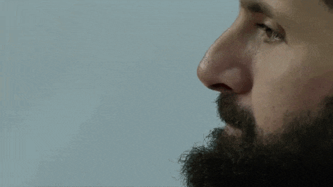 a close up of a man 's face with a beard and a blue background .