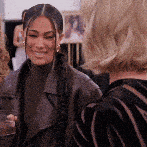 a woman in a braided ponytail is smiling while talking to another woman .
