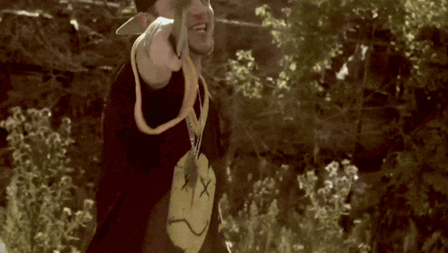 a man wearing a black shirt with a smiley face and a necklace with the letter x on it