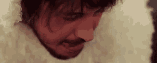 a close up of a man 's face with a beard and a white fur coat .