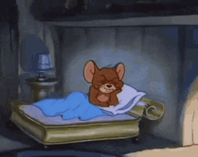 a cartoon mouse is laying on a bed with a pillow and a blanket .