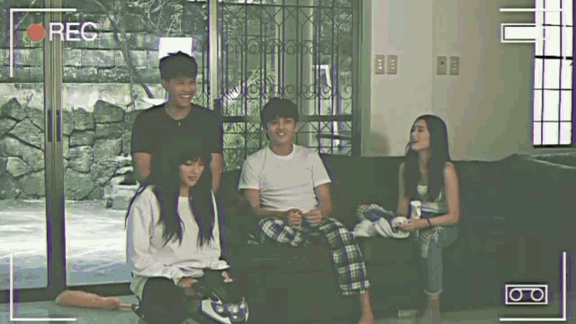 a group of people are sitting on a couch with a recorder recording them
