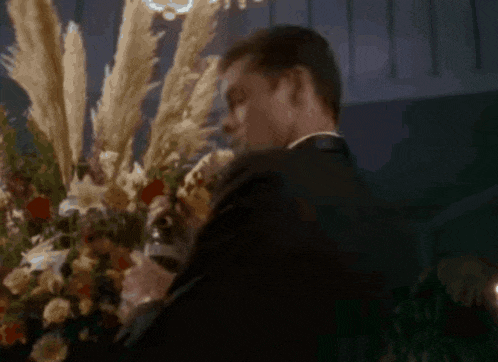 a man standing in front of a vase of flowers