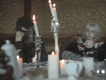 a woman sitting at a table with candles and a gif that says aespagifs on it