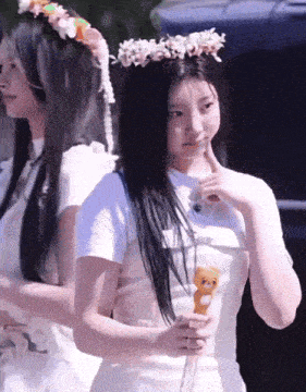 a girl with a flower crown on her head is holding a stuffed animal