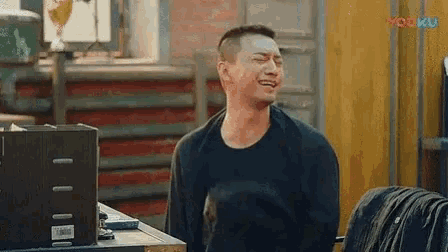 a man is laughing while sitting at a table in front of a laptop computer .