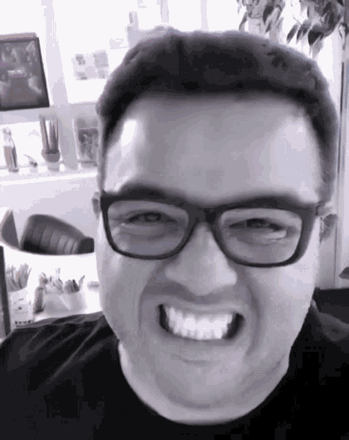 a man wearing glasses and a black shirt smiles for the camera