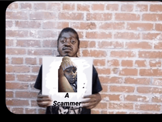 a man holds up a sign that says a scammer