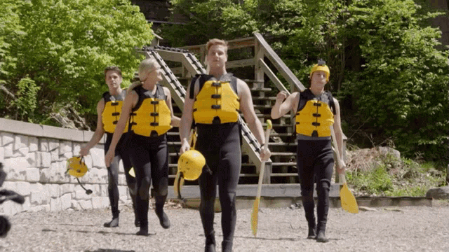 a group of people wearing life jackets are walking down a path