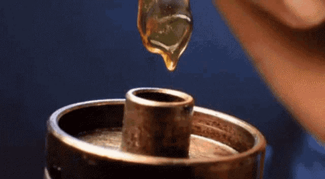 a drop of honey is being poured into a metal object .