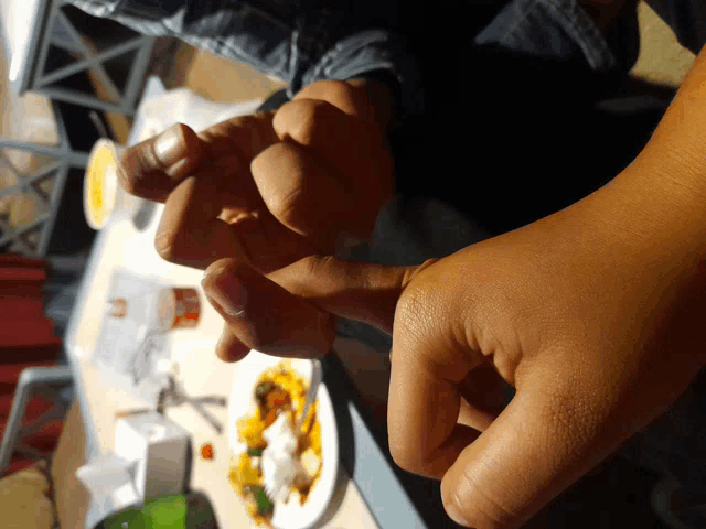 a close up of a person 's hands with food in the background