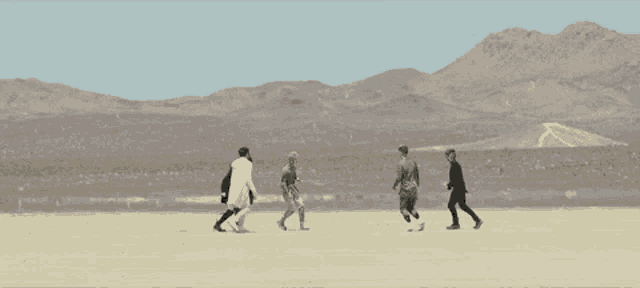 a group of people are standing in the desert near a cactus .