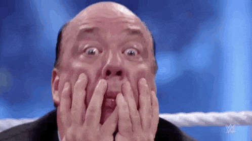 a bald man is sitting in a wrestling ring covering his face with his hands .