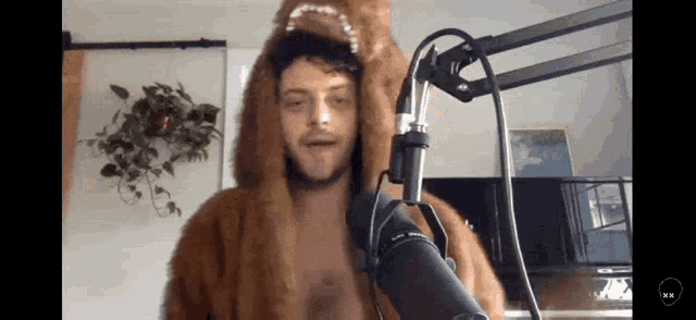 a man in a fur coat is standing in front of a microphone