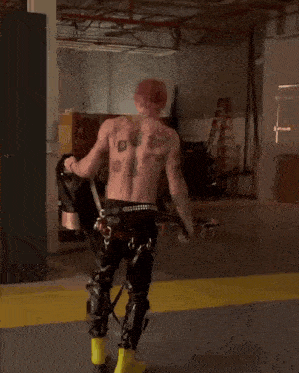 a shirtless man with tattoos on his back is walking in a room