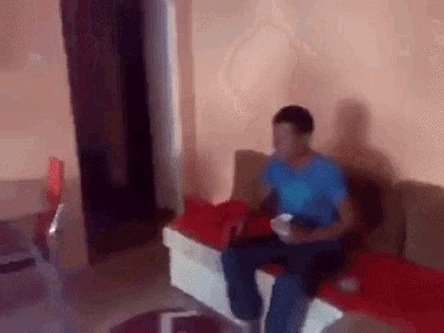 a man is sitting on a couch in a living room holding a cup .