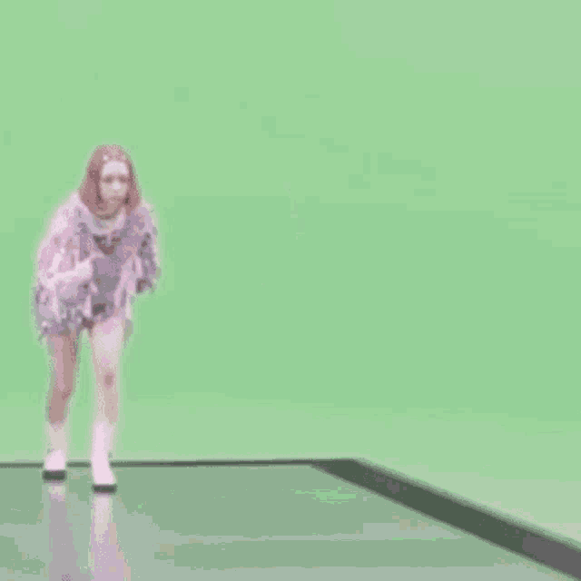a woman is dancing on a green screen while wearing a purple dress .