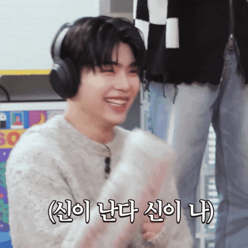 a man wearing headphones and a sweater is smiling in a foreign language