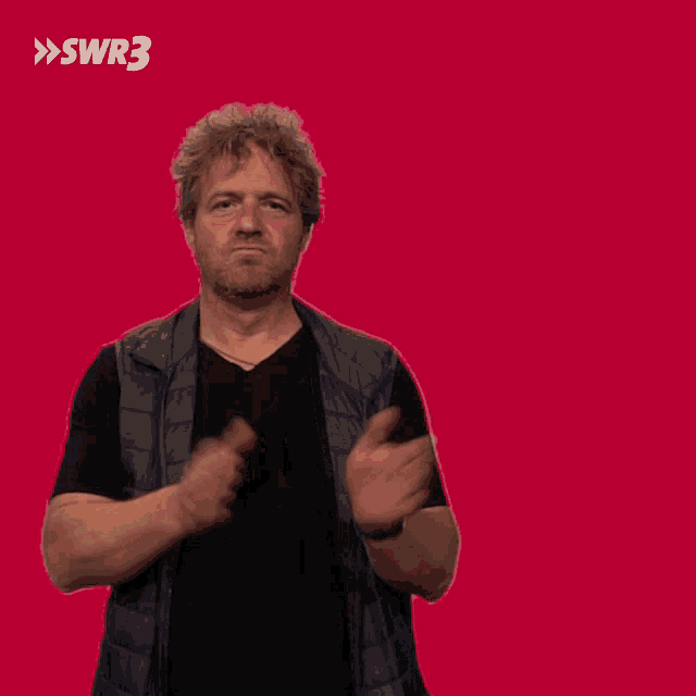 a man applauds in front of a red background with swr3 in white