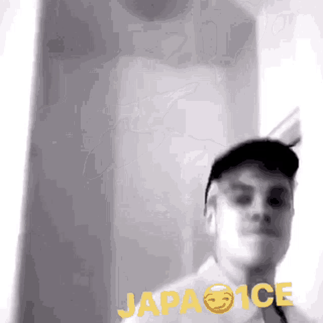 a man wearing a baseball cap is standing in front of a wall with the word japa ice on it