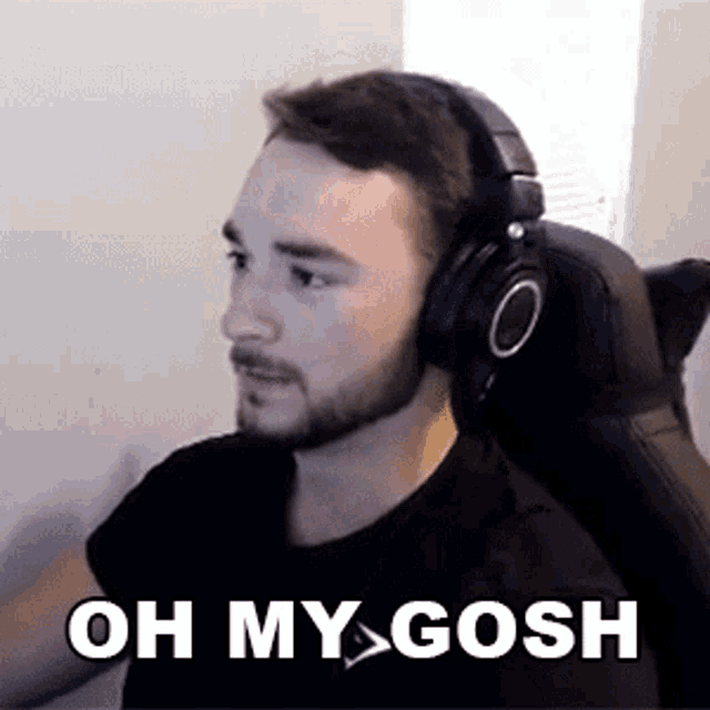 a man with a beard wearing headphones is sitting in a chair and saying `` oh my gosh '' .