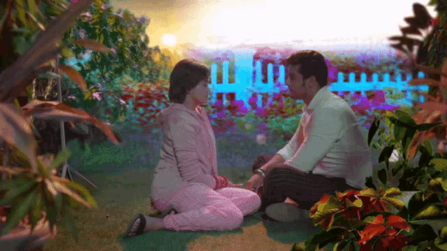 a man and a woman are sitting on the ground holding hands