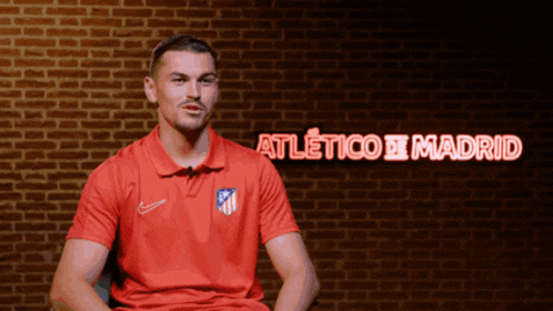 a man wearing a red shirt that says atletico madrid on it