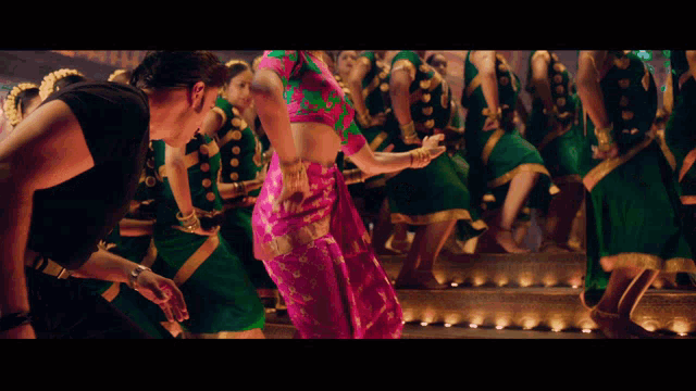a man in a black shirt is dancing with a woman in a pink and green dress