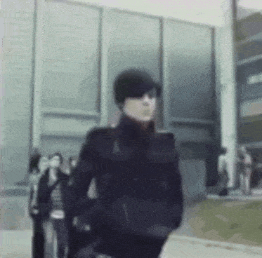 a man wearing a hat and sunglasses is walking down a street .