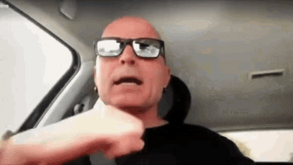 a bald man wearing sunglasses is sitting in a car and talking .