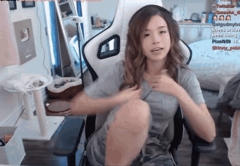 a woman is sitting in a chair with a cat tree in the background and a sign that says " kneecap been doing "