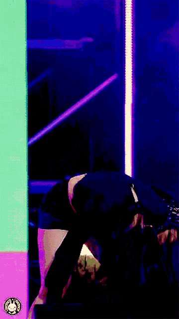 a person is kneeling down in front of a purple wall with a sticker that says ' a ' on it