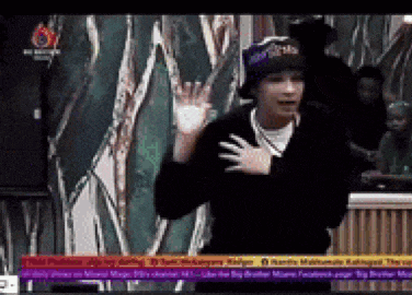 a man wearing a hat and a black jacket is dancing on a tv screen
