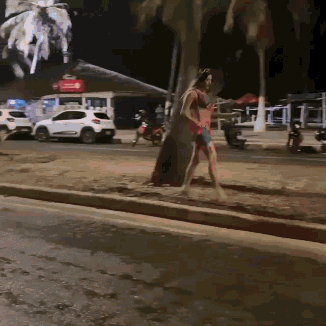 a woman in a bikini is walking down the street