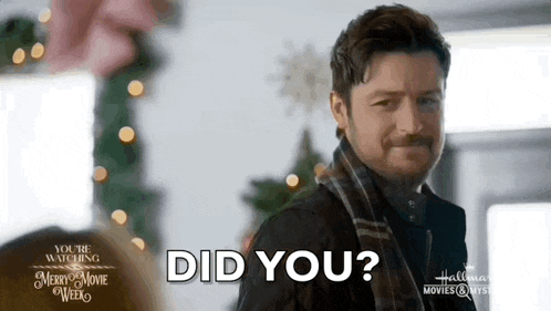 a man wearing a scarf is standing in front of a christmas tree and asking , `` did you ? ''