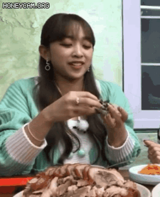 a woman is sitting at a table eating meat .