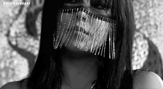 a black and white photo of a woman wearing a mask with fringe