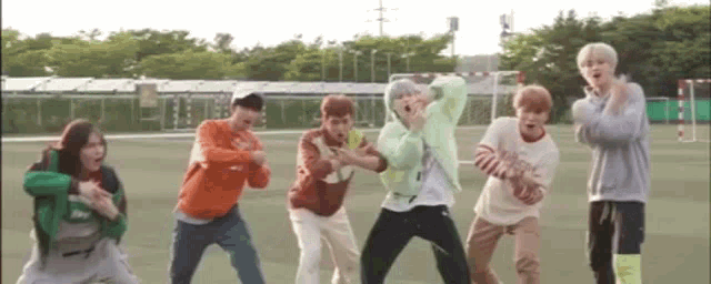a group of young people are standing next to each other on a field and dancing .