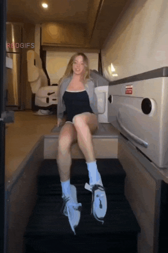 a woman is sitting on a set of stairs with the word redgifs on the bottom right corner